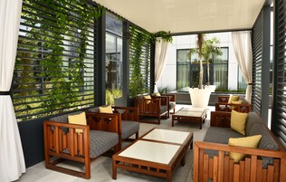 Un área de estar moderna al aire libre con mobiliario de madera, una planta grande en maceta y vistas a la ciudad.