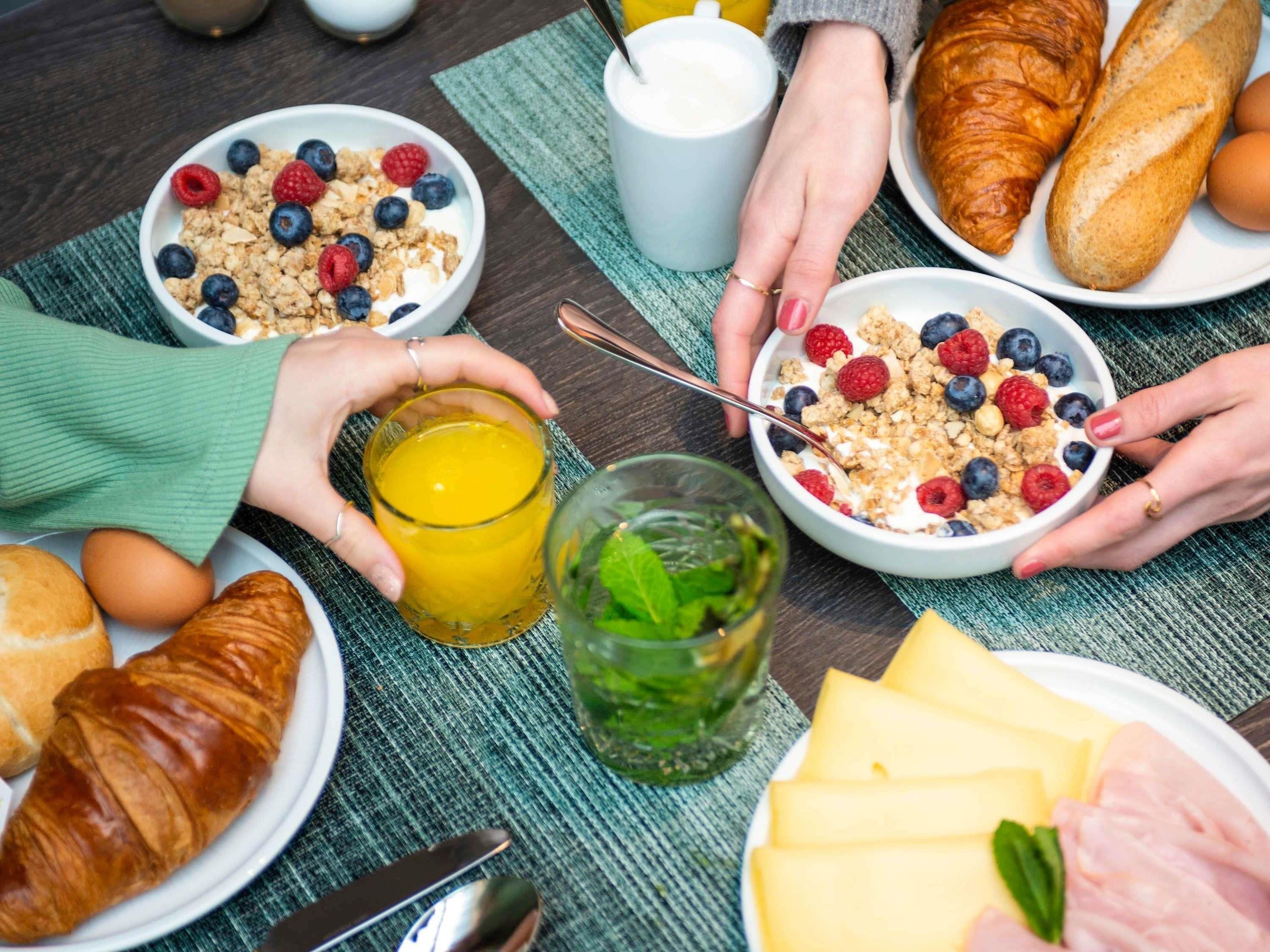 Un desayuno con cruasanes, queso, jamón y un vaso de zumo de naranja.