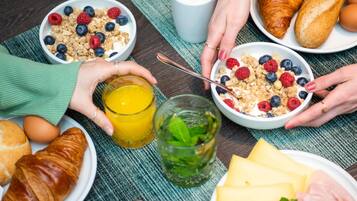 Un desayuno con cruasanes, queso, jamón y un vaso de zumo de naranja.