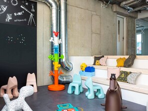 Une piÚce avec un tableau noir, une structure de jeu et un canapé avec des coussins.