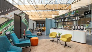 Un intérieur moderne avec un plafond haut, des poutres en bois, un espace bar et différents coins salon.