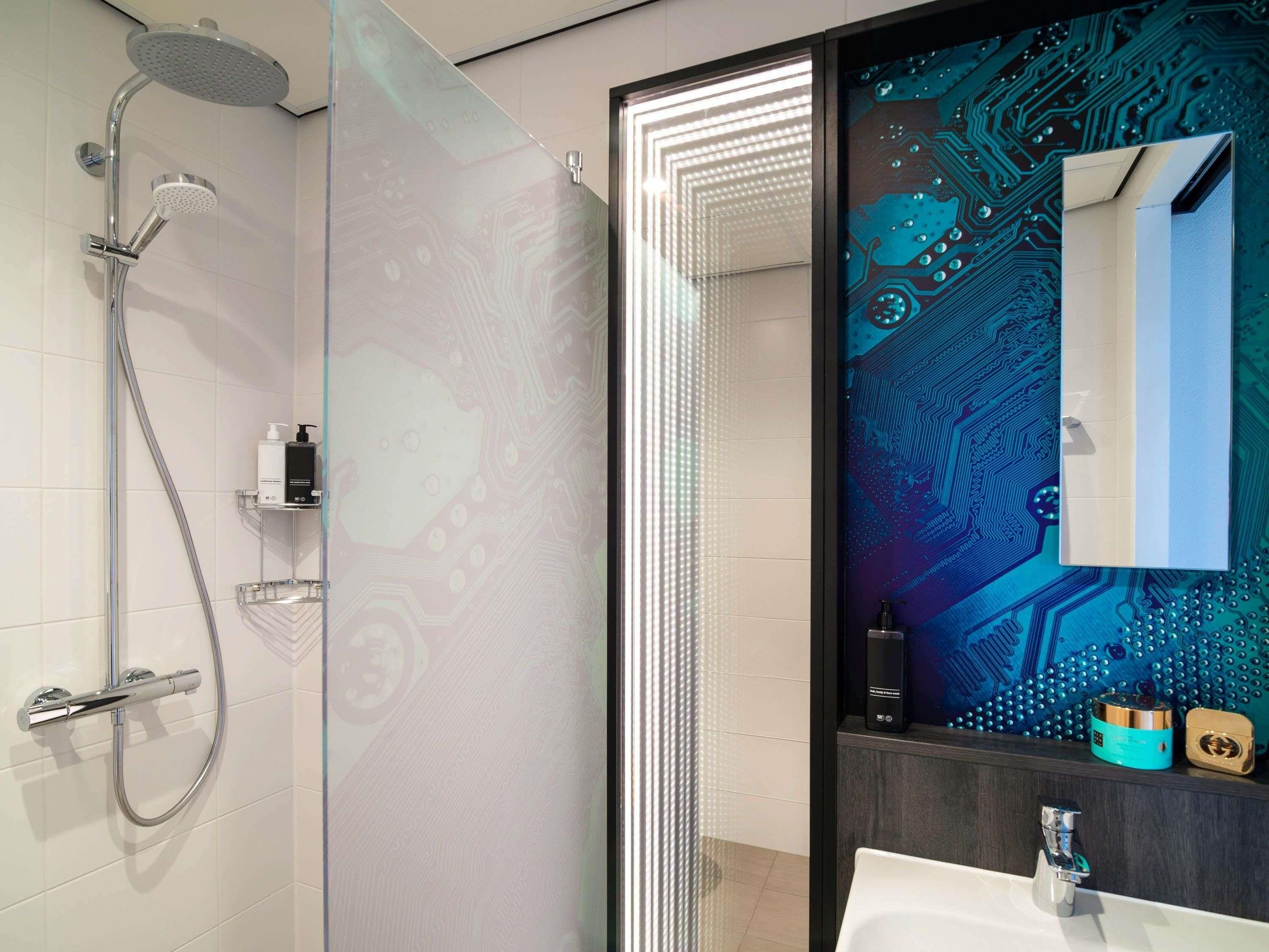 Een moderne badkamer met een douche, een wastafel en een spiegel met een printplaatontwerp.