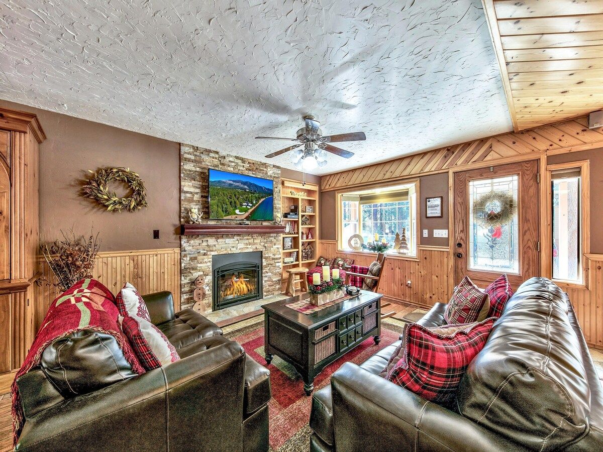 A cozy living room with a fireplace, leather sofas, a coffee table, and a bookshelf.