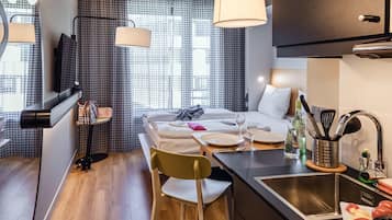 Et lille hotelværelse med seng, sengebord og et tekøkken.