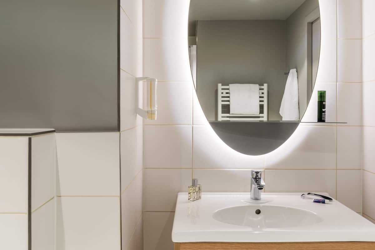 A modern bathroom with a white sink, a mirror, and a towel rack.