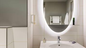Ein modernes Badezimmer mit einem weißen Waschbecken, einem Spiegel und einem Handtuchhalter.