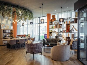Une bibliothèque moderne avec une table en bois, des sièges confortables et une étagère remplie de livres et de jouets.