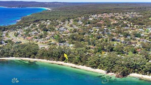 An aerial view of a coastal residential area with houses, roads, and a beach.