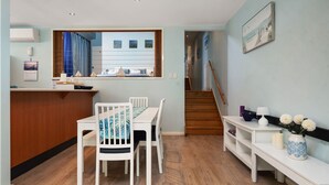 A modern kitchen with a dining area, wooden flooring, and a staircase leading to another level.