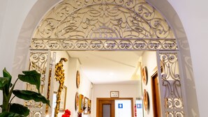 An ornate entrance with a decorative archway, a mirror, and framed pictures on the walls. - CHIC-ALAMEDA (Sevilla)
