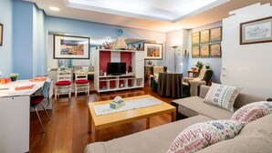 A living room with a wooden coffee table, a sofa, a TV, and a bookshelf. - CHIC-ALAMEDA (Sevilla)