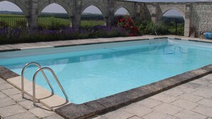 A swimming pool with a stone bridge in the background. - Gite du Manoir des Roches (SAIRES)