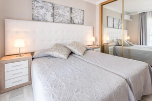 A hotel room with a large bed, two bedside tables with lamps, a mirror, and artwork on the wall. - Marbella Resort Townhouse (Marbella)