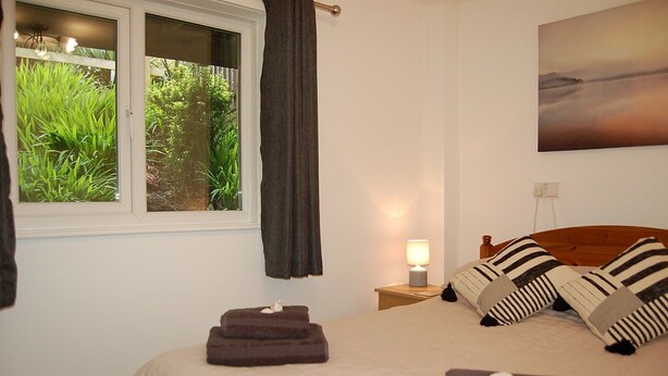 A bedroom with a bed, pillows, a nightstand, a lamp, and a window with curtains. - No 6 at Dolgoch Falls Cottages (Bryncrug)