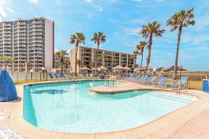 A swimming pool with lounge chairs and palm trees, surrounded by hotel buildings. - Saida 1 404 - 2 bdrm/2 bath, recently renovated at South Padre Island's premier resort (South Padre Island)