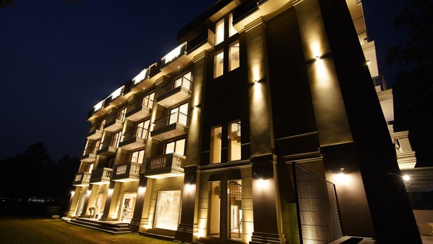 Et flereetagers hotel med oplyste balkoner og en godt oplyst indgang.