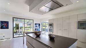 Una cocina moderna con una isla grande, electrodomésticos de acero inoxidable y una puerta corrediza de vidrio que da a un patio.