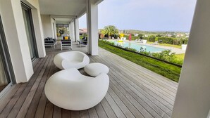 Una terraza moderna al aire libre con asientos blancos de formas originales, una piscina y vistas al paisaje.