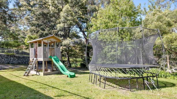 A playground with a slide and a trampoline enclosed by a safety net.