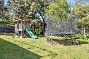 A playground with a slide and a trampoline enclosed by a safety net.
