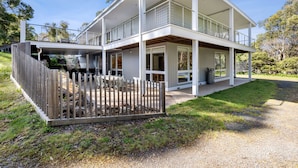 A two-story modern house with a covered patio and a fenced yard.