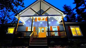 A house with a covered porch, a front door, and a staircase leading up to the entrance. - Cozy Cabin with Mountain Views, Pet Friendly, 3 Miles from Downtown Highlands (Highlands)