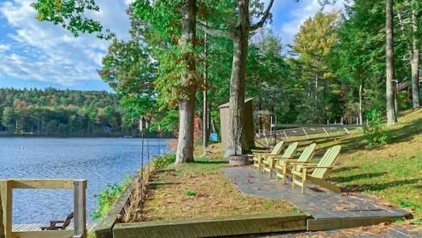 Une terrasse au bord du lac, avec des chaises en bois et une petite structure en bois.