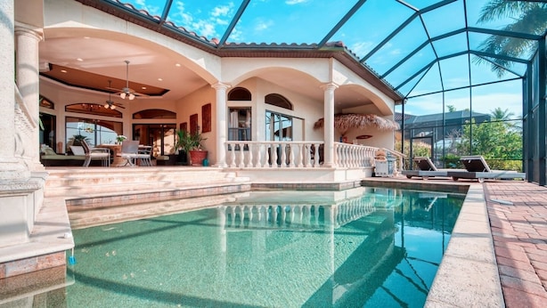 Ein luxuriöser Poolbereich mit klarem Pool, einer überdachten Terrasse mit Sitzgelegenheiten und Blick auf die umliegende Landschaft.