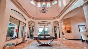 Ein geräumiges Foyer mit einem zentralen Tisch, großen Fenstern und einer Chandelier.