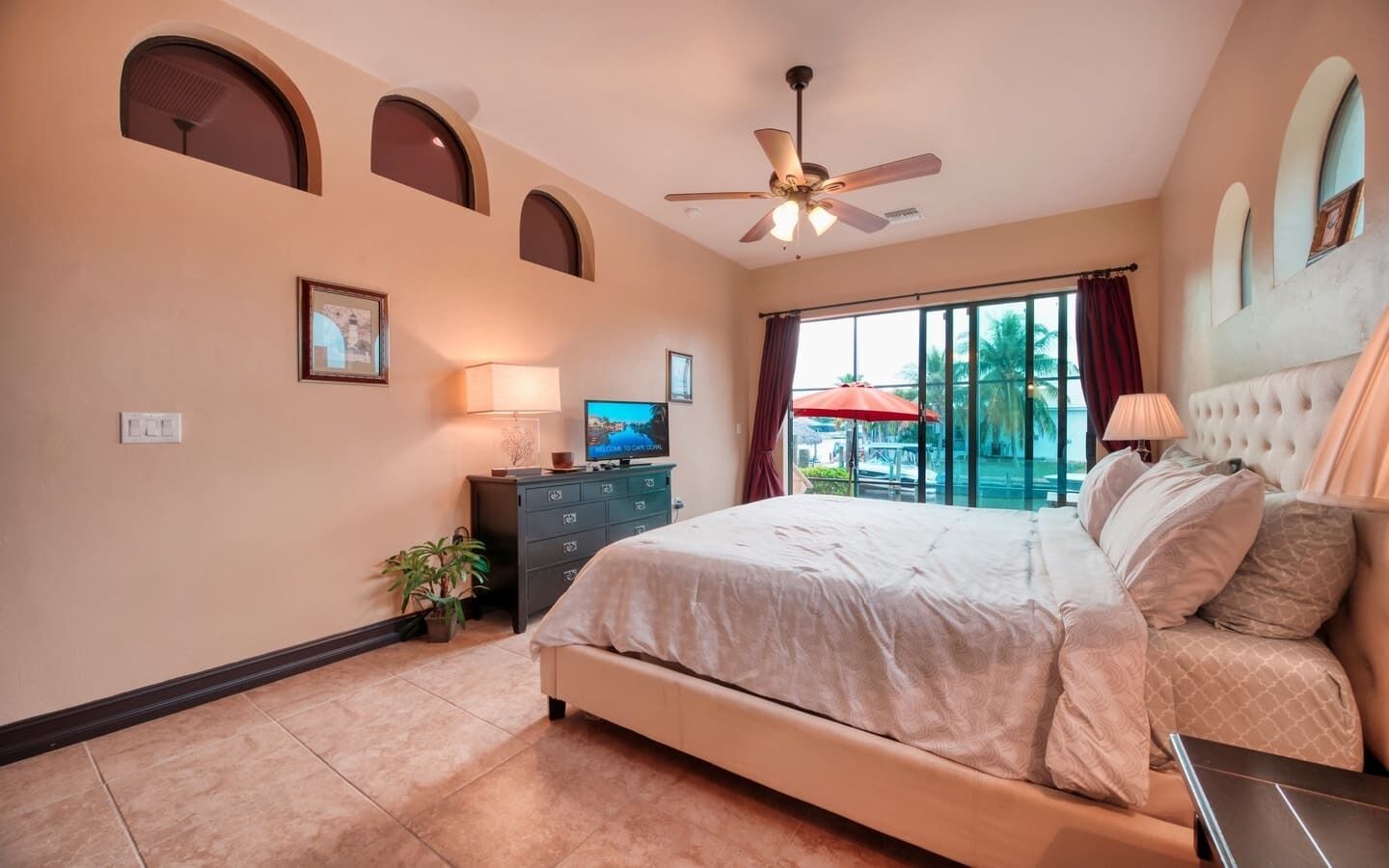 A bedroom with a bed, a TV, a dresser, and a window with curtains.