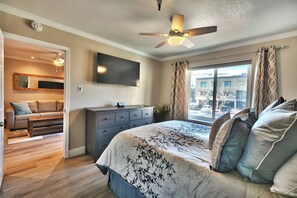 A bedroom with a bed, a dresser, a television, a ceiling fan, and a window with curtains. - Carriage House 1BR | Ski Slope Views | Fireplace | Pool & Hot Tub (Park City)