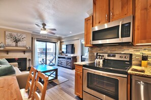 A modern kitchen with stainless steel appliances, wooden cabinets, and a dining area with a table and chairs.