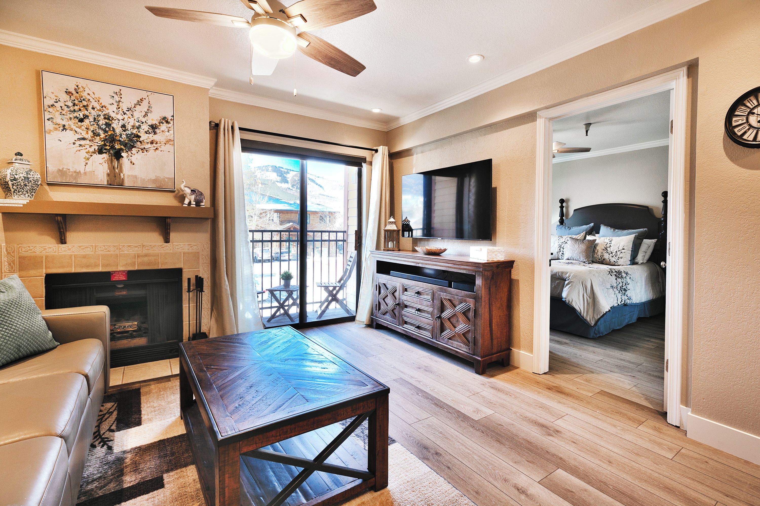 A living room with a fireplace, a television, and a bed in the adjacent room.