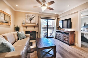 A living room with a fireplace, a television, and a ceiling fan.