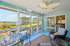 A covered outdoor area with a view of the sea, a dining table, chairs, and a wicker sofa. - Overlook the Cailbogue Sound On Your Private Deck (Hilton Head Island)