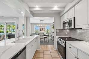 A modern kitchen with white cabinetry, stainless steel appliances, and a central island. - Overlook the Cailbogue Sound On Your Private Deck (Hilton Head Island)