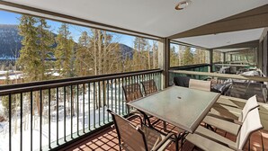 A balcony with a table and chairs, overlooking a snowy landscape and trees. - Keystone Condo in Quiet Location w/ Private Balcony for Great Mountain Views (Keystone)