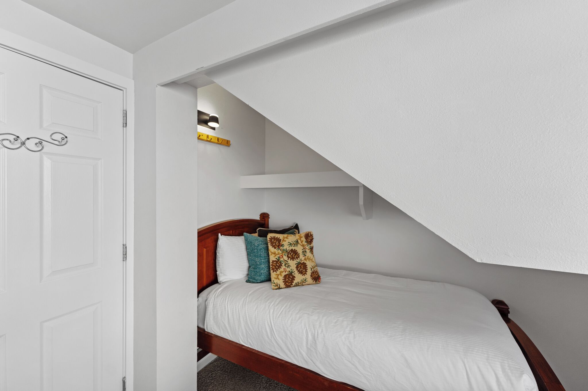 A bedroom with a wooden bed, white walls, and a slanted ceiling.