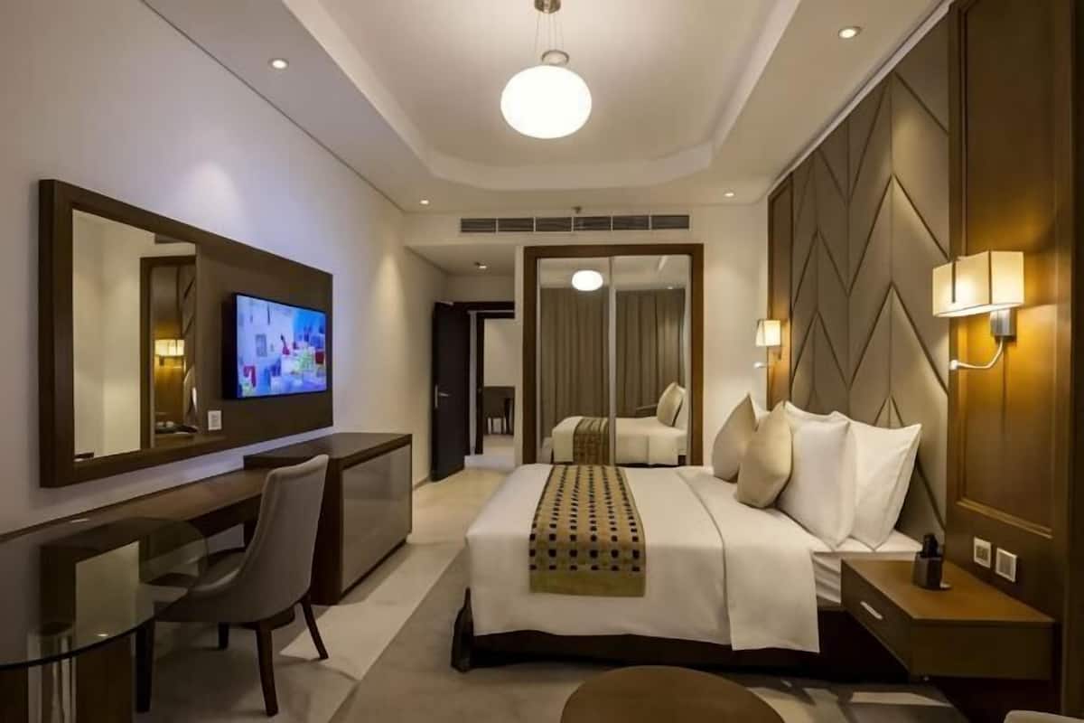 A hotel room with a bed, a desk, a television, and a mirror.