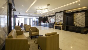 Um hall moderno com assentos, balcão de recepção e área de mármore.