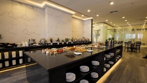 Disposição de buffet com diversos alimentos e uma área de estar com cadeiras.