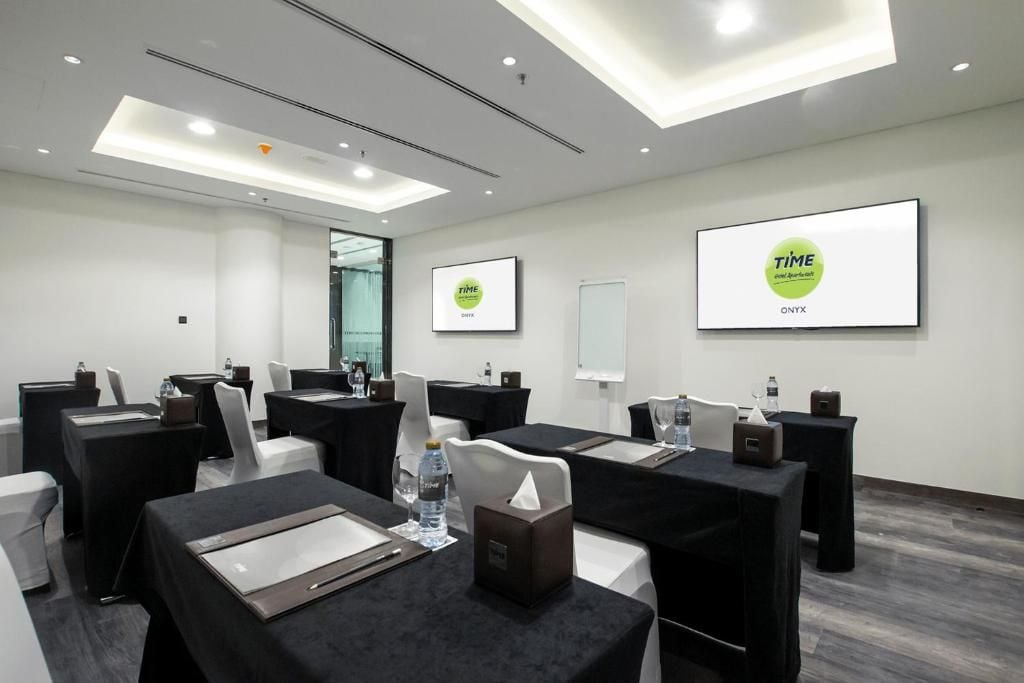 Une salle de conférence équipée de tables, de chaises et d’écrans de présentation.