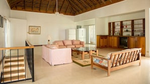 A spacious living area with a high ceiling, a sofa, a coffee table, and a television. - Villa Roma (Montego Bay)
