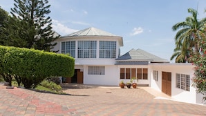 A two-story house with a large garage, a paved driveway, and a well-maintained garden. - Villa Roma (Montego Bay)
