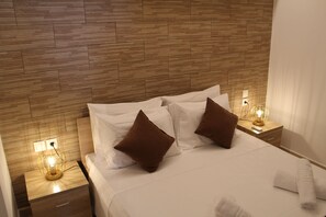 Relax in a stylish room with a neatly made bed, wooden headboard, and a nightstand with a lamp.