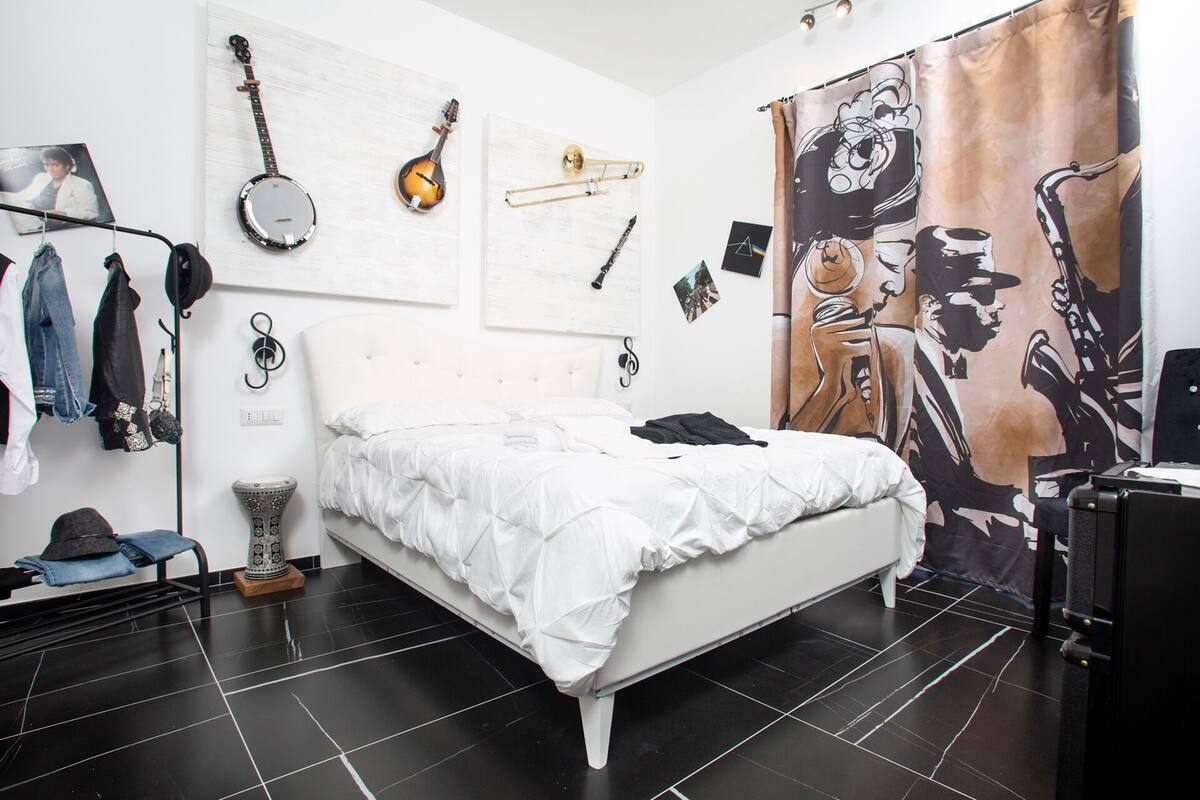 A bedroom with a bed, a guitar, a trombone, and a poster on the wall.