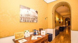 Ein Empfangsbereich mit einem Holztisch, einem gerahmten Foto eines Gebäudes und einem Schild mit der Aufschrift 'Piazza Di Spagna View'.