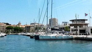 Un puerto deportivo con varias embarcaciones amarradas, un edificio con un letrero y cielo despejado.