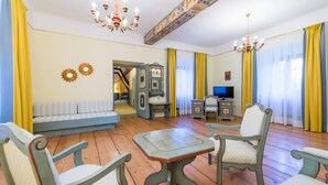 A living room with a sofa, two armchairs, a small table, a television, and a decorative mirror. - Hotel Kartause (Gaming)