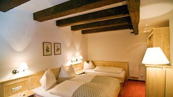 A hotel room with two beds, wooden beams, a radiator, and wall-mounted lamps.